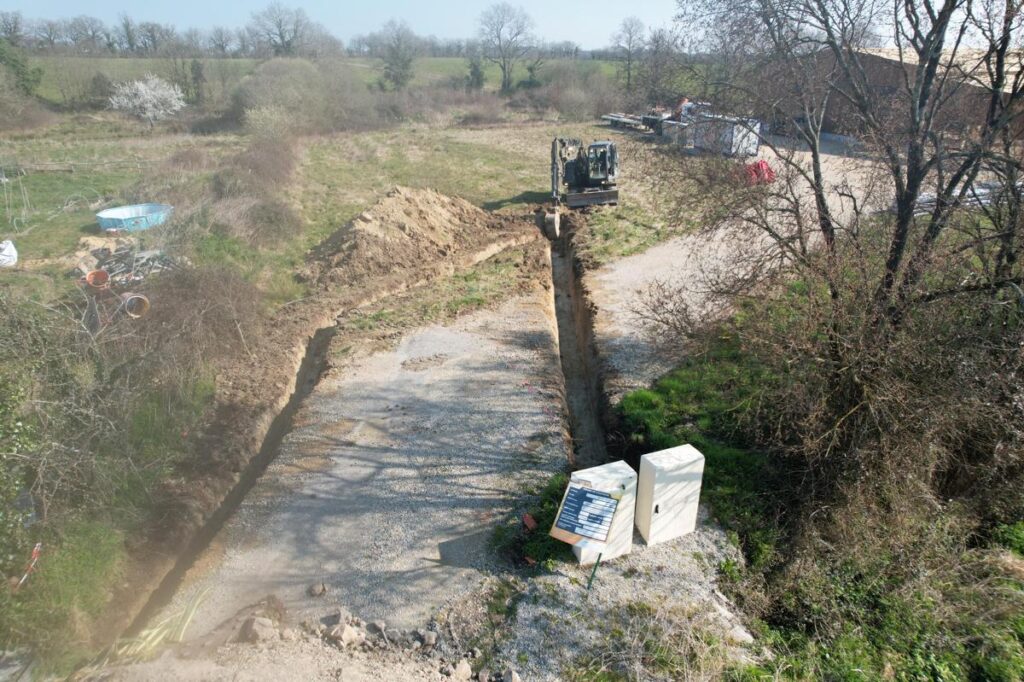 Vue aérienne d’un chantier de construction avec une structure en bois en cours de montage, un espace excavé en préparation, des engins de chantier